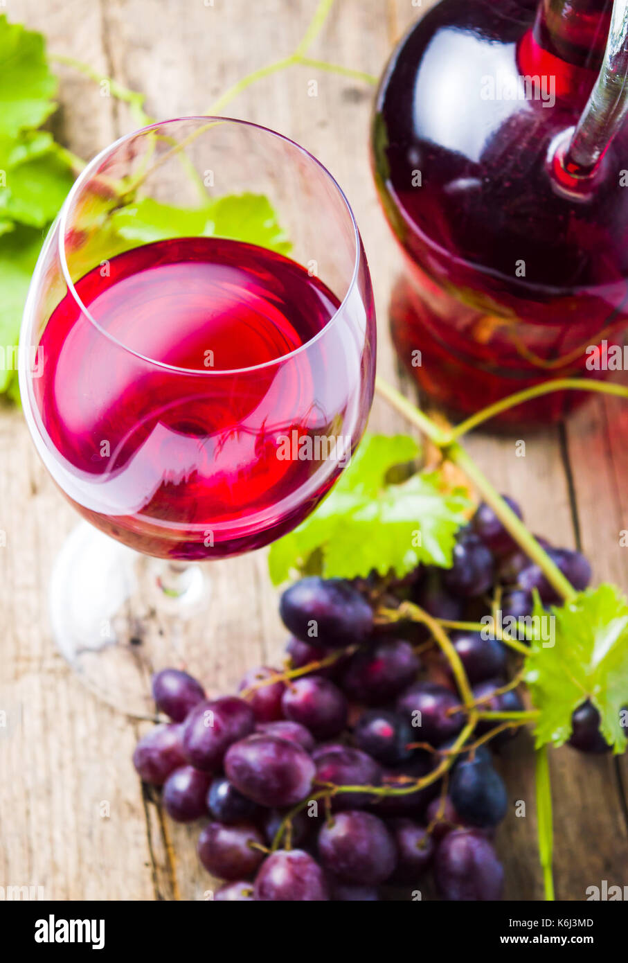 Glas Rotwein mit Trauben auf einem rustikalen Holzmöbeln Hintergrund Stockfoto