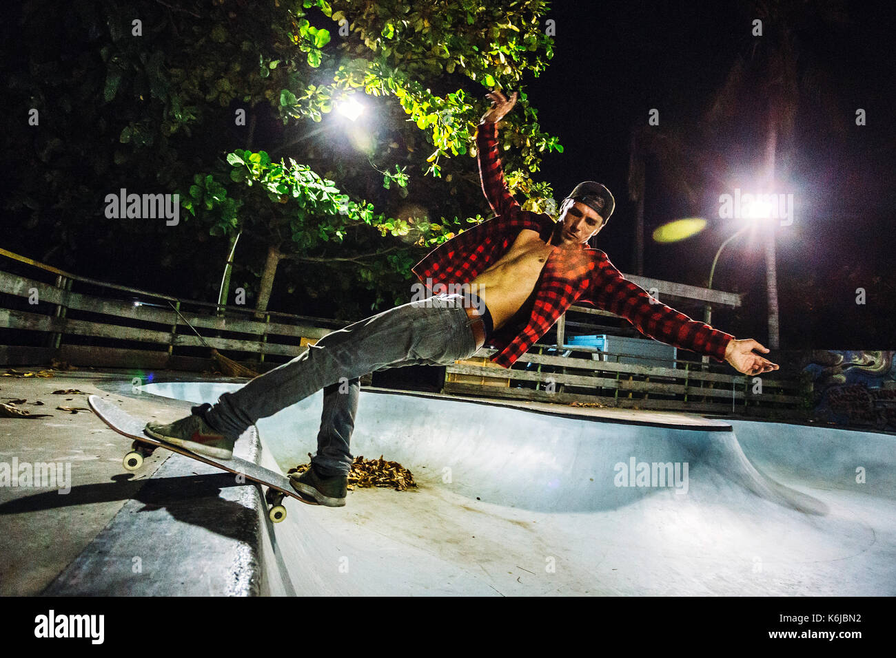 Seitenansicht der Mann mit dem Skateboarden beleuchtete Skate Park bei Nacht, Jimbaran, Bali, Indonesien Stockfoto
