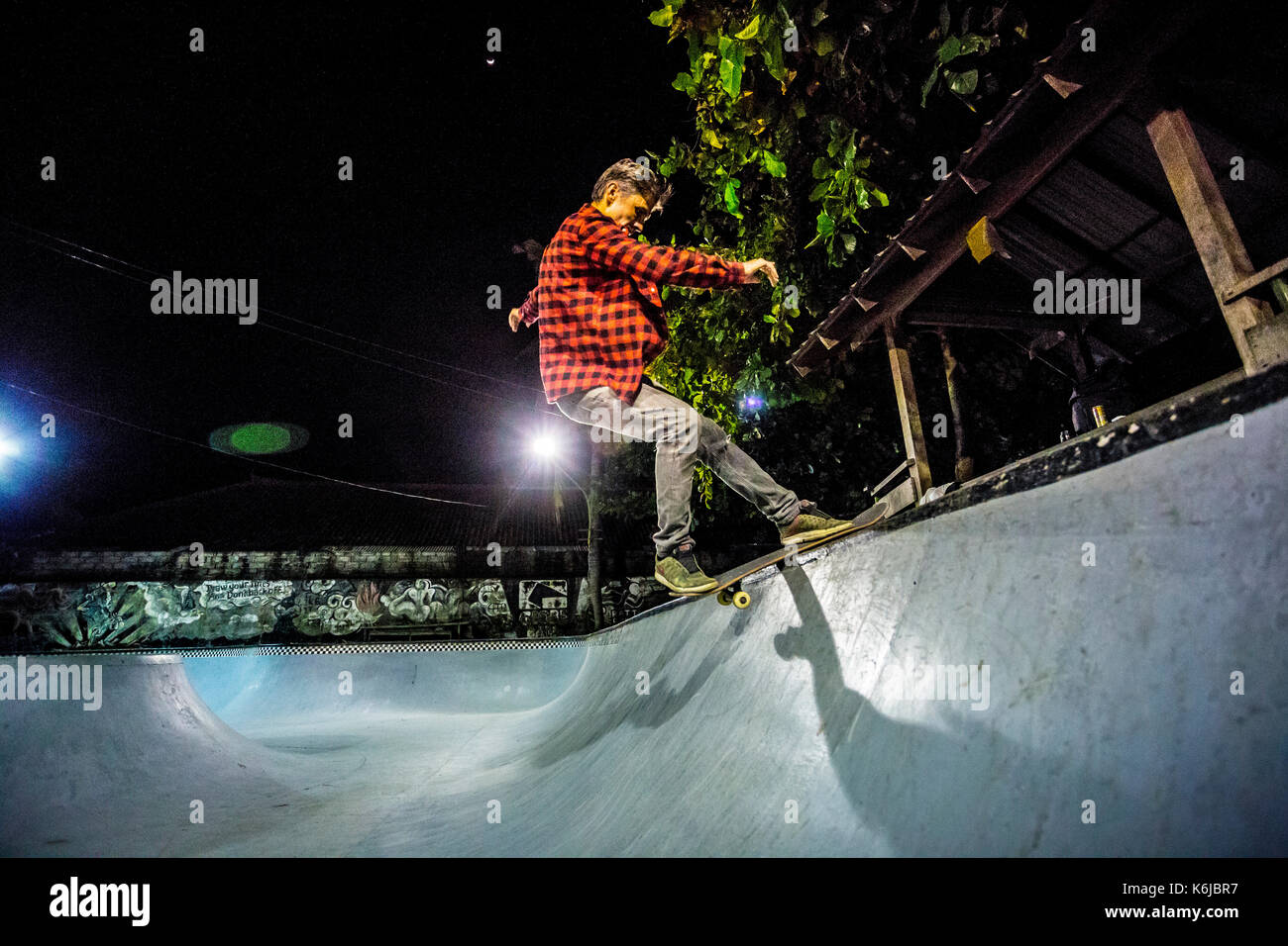 Man Balancieren auf Skateboard in beleuchteten Skate Park bei Nacht, Jimbaran, Bali, Indonesien Stockfoto