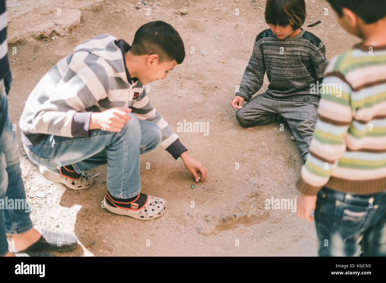 Westler Junge spielt Murmeln in der Straße mit marokkanischen Kinder, Marrakesch, Marokko Stockfoto