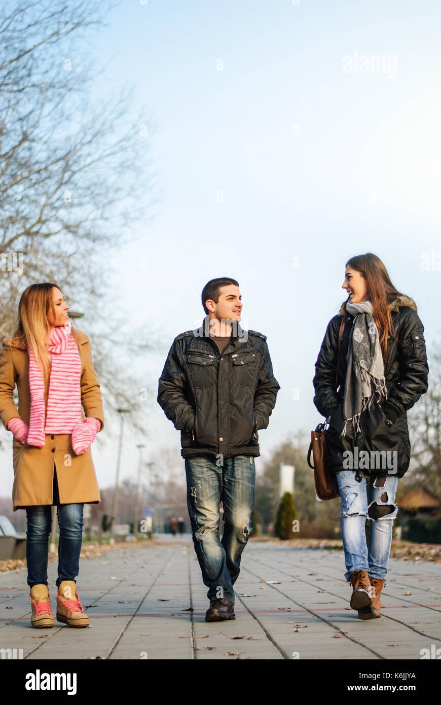 Zwei junge Mädchen im Teenageralter und ein Kerl auf der Straße und Reden Stockfoto