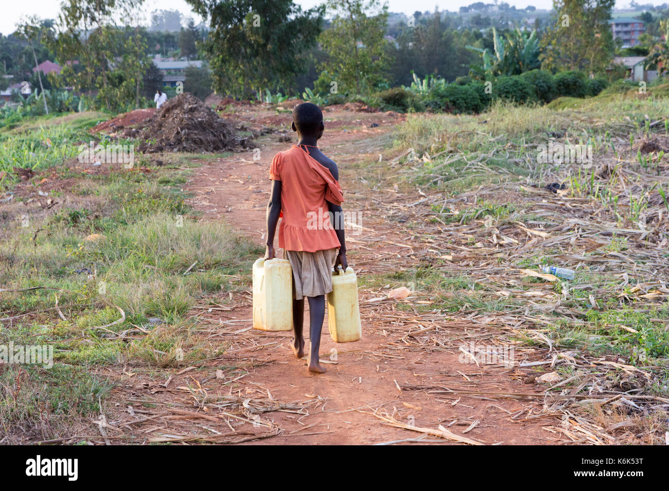 Ein junges Mädchen weg die Kanister voll Wasser. Sie ist in Lumpen gekleidet. Stockfoto