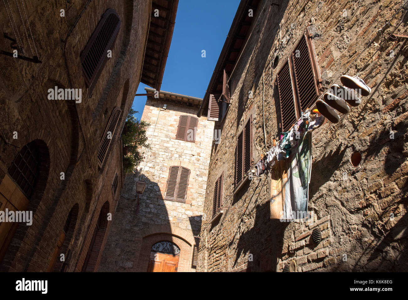 Waschen heraus hängen auf einer Linie zu trocknen, hoch oben aus dem Fenster eines Hauses in San Gimignano, Toskana Italien Europa EU Stockfoto