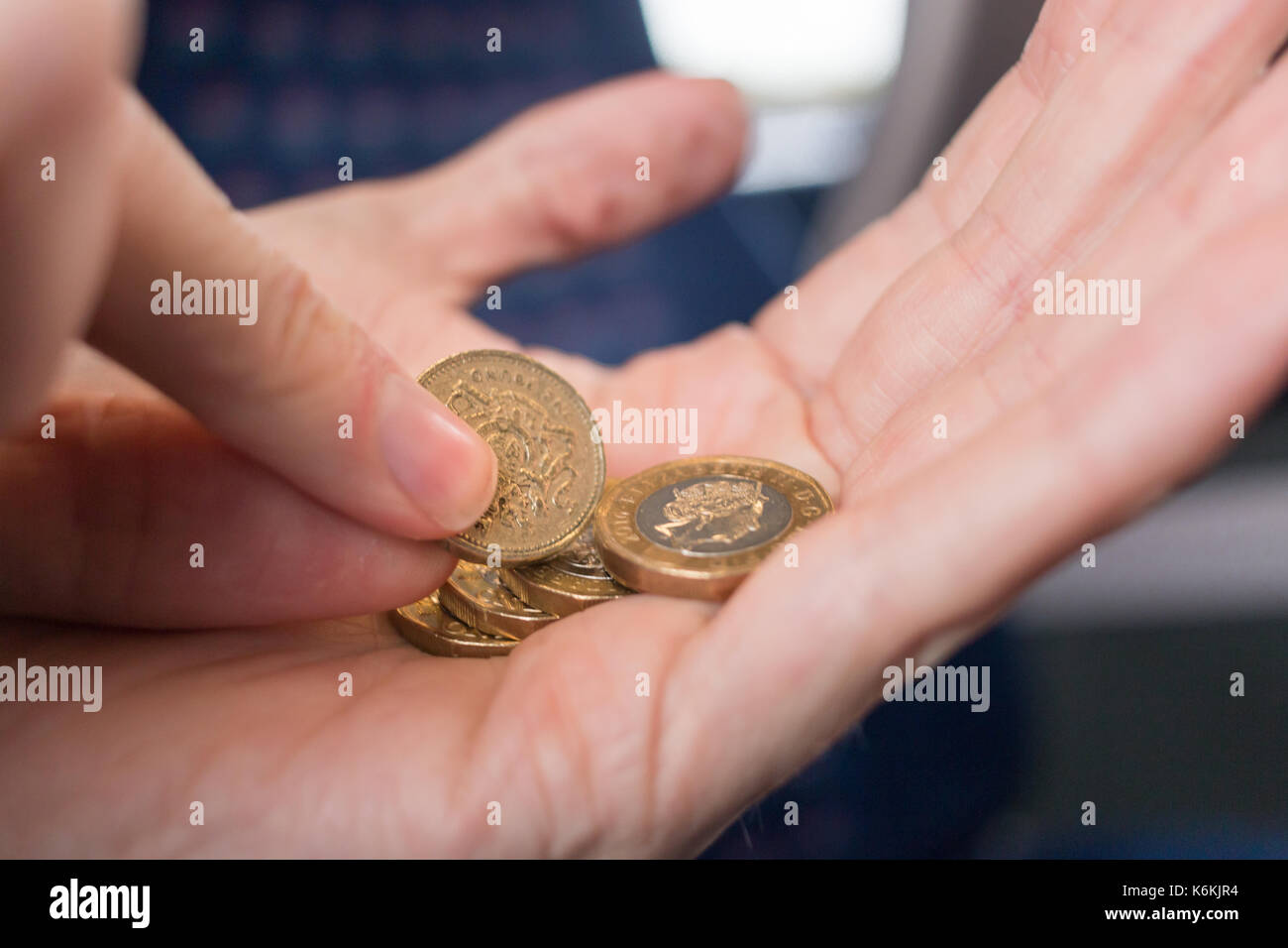 Kommissionierung, einem alten pound Münze aus einer Handvoll neuer Pfund Münzen Stockfoto