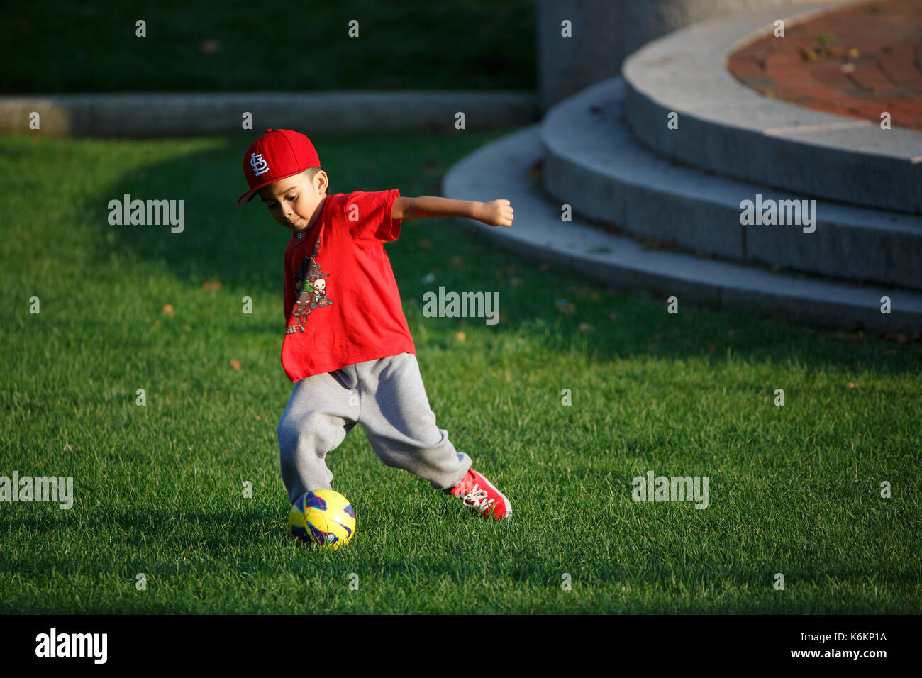 Jungen spielen mit Fußball im City Park Stockfoto