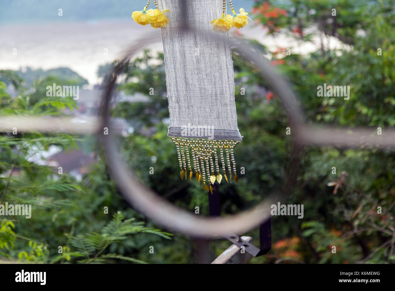 Dekorative Textilband flattert im Wind. Flagge mit Blumen winken in Wind am Mount Phousi in Laos, Blick durch das Geländer. Stockfoto