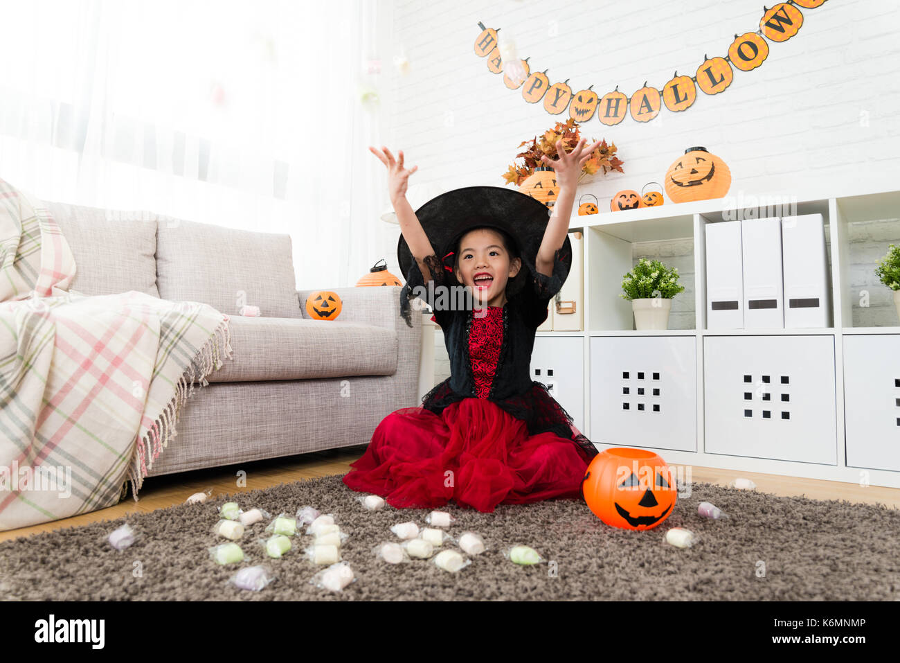Süße Mädchen werfen Bonbons in den Himmel zu feiern Sie eigenen vielen Süßigkeiten aus Halloween Trick oder Spiel zu Hause behandeln Stockfoto