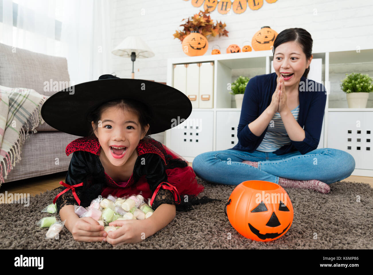 Wenig begeistert Mädchen ihre süsse bonbons Holding gab vom Nachbarn für Halloween Spiel Trick oder mit ihrer Mama behandeln. Stockfoto