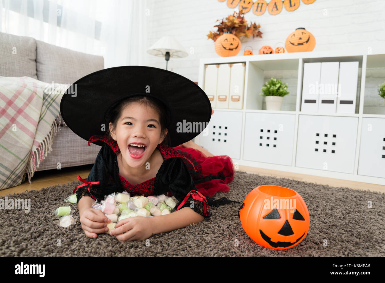 Niedliche Happy girl Holding ihr süßen Süßigkeiten aus dem Kürbis für Halloween Spiel Trick oder Festlichkeit. Stockfoto