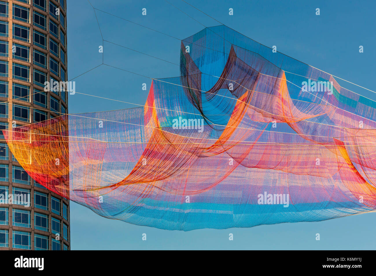 Bänder in den Himmel über Boston - Die farbenfrohe Janet Echelman", als ob es Schon hier "aerial Skulptur über Boston's Rose Kennedy Greenway ausgesetzt. Die Skulptur ist von Hand gefertigt - spleißen Seil und verknoten Garn in einer vernetzten Mesh von mehr als einer halben Million Teilnehmern. Wenn eines ihrer Elemente bewegt, jedes andere Element ist betroffen. Stockfoto