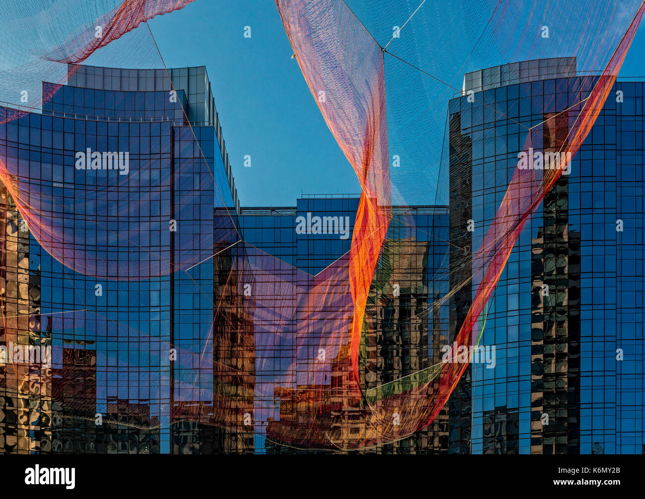 Boston Fassade Reflexionen - Die farbenfrohe Janet Echelman", als ob es Schon hier "aerial Skulptur über Boston's Rose Kennedy Greenway mit Reflexionen über das InterContinental Hotel Fassade ausgesetzt. Die Skulptur ist von Hand gefertigt - spleißen Seil und verknoten Garn in einer vernetzten Mesh von mehr als einer halben Million Teilnehmern. Wenn eines ihrer Elemente bewegt, jedes andere Element ist betroffen. Stockfoto