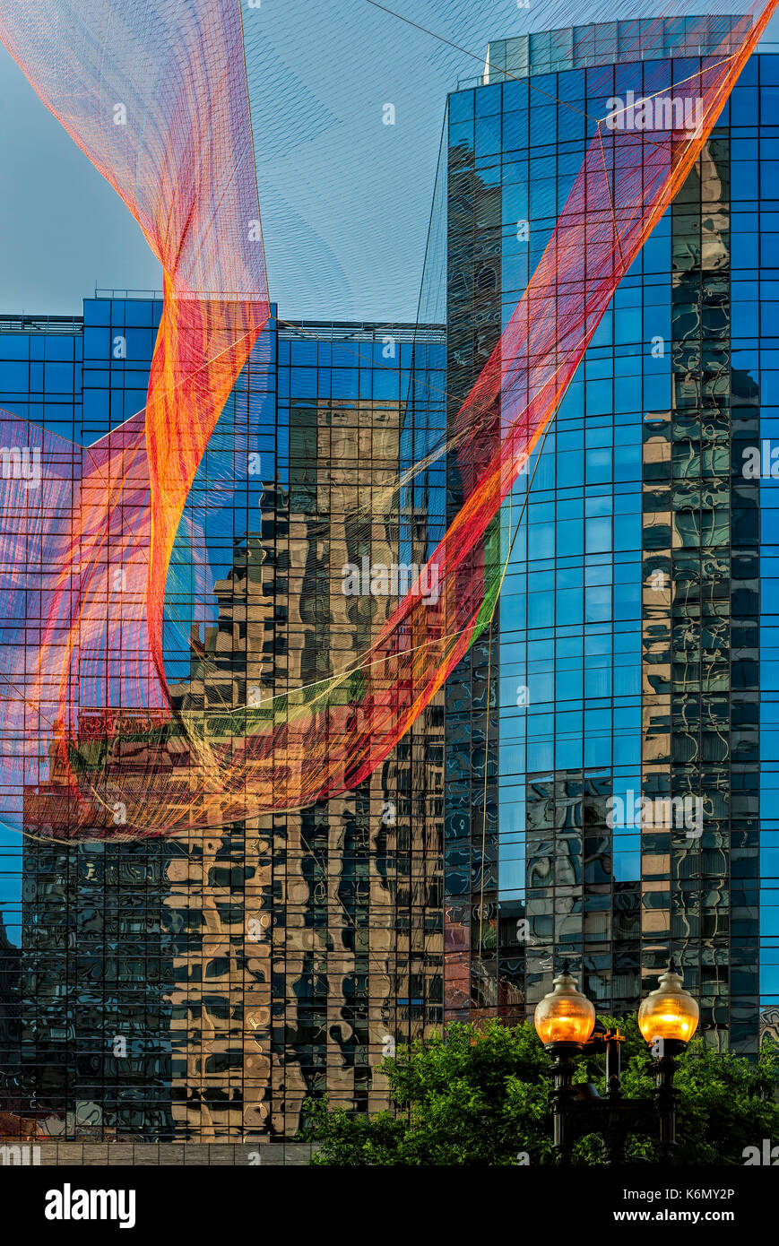 Boston Reflexionen - Die farbenfrohe Janet Echelman", als ob es Schon hier "aerial Skulptur über Boston's Rose Kennedy Greenway mit Reflexionen über das InterContinental Hotel Fassade ausgesetzt. Die Skulptur ist von Hand gefertigt - spleißen Seil und verknoten Garn in einer vernetzten Mesh von mehr als einer halben Million Teilnehmern. Wenn eines ihrer Elemente bewegt, jedes andere Element ist betroffen. Stockfoto