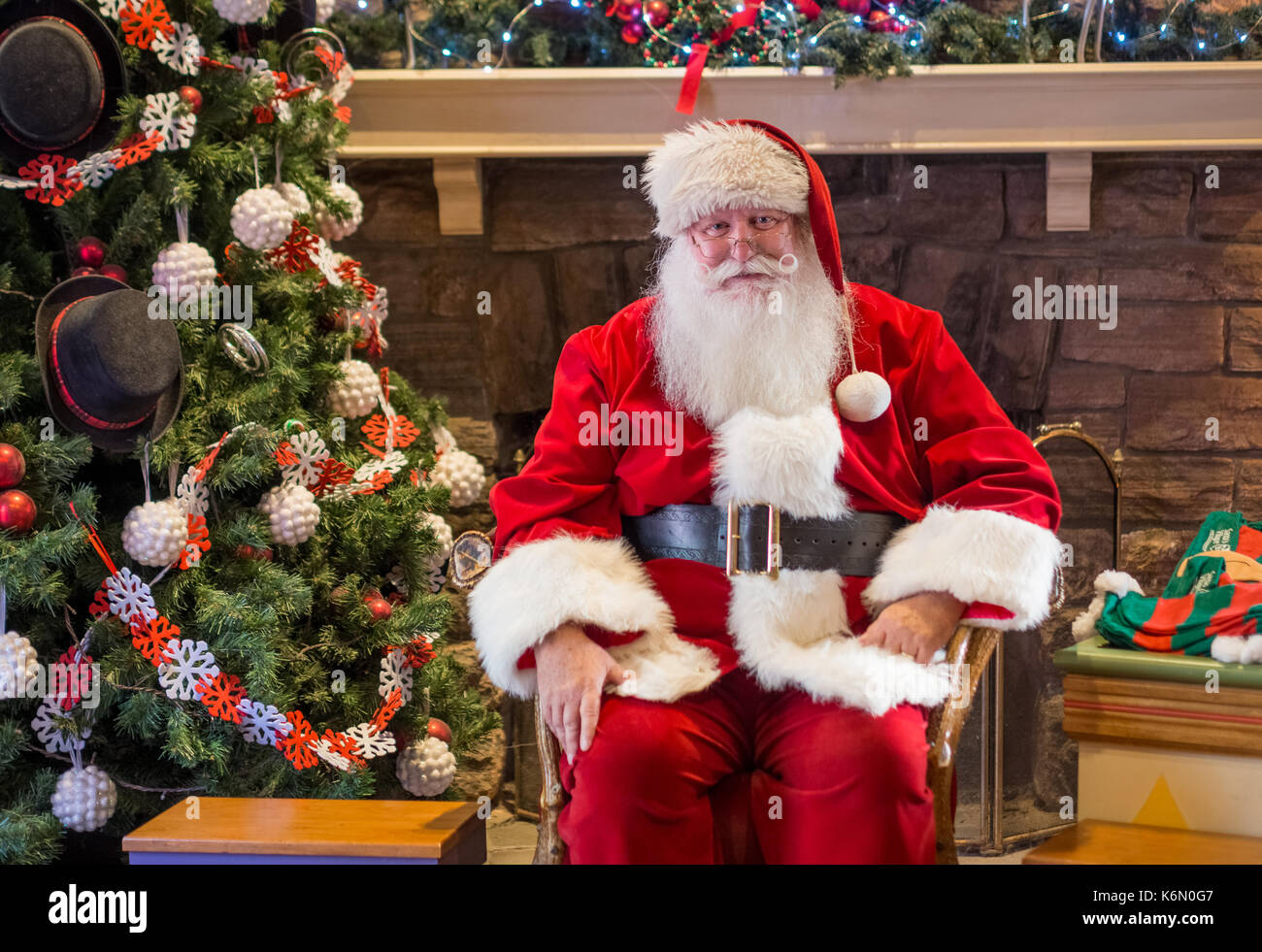 Sant warten auf Kinder zu erhalten, die ihren Urlaub in ein Hallenbad Einstellung geklickt haben. Der Hintergrund zeigt einen geschmückten Weihnachtsbaum mit Ornamenten. Stockfoto