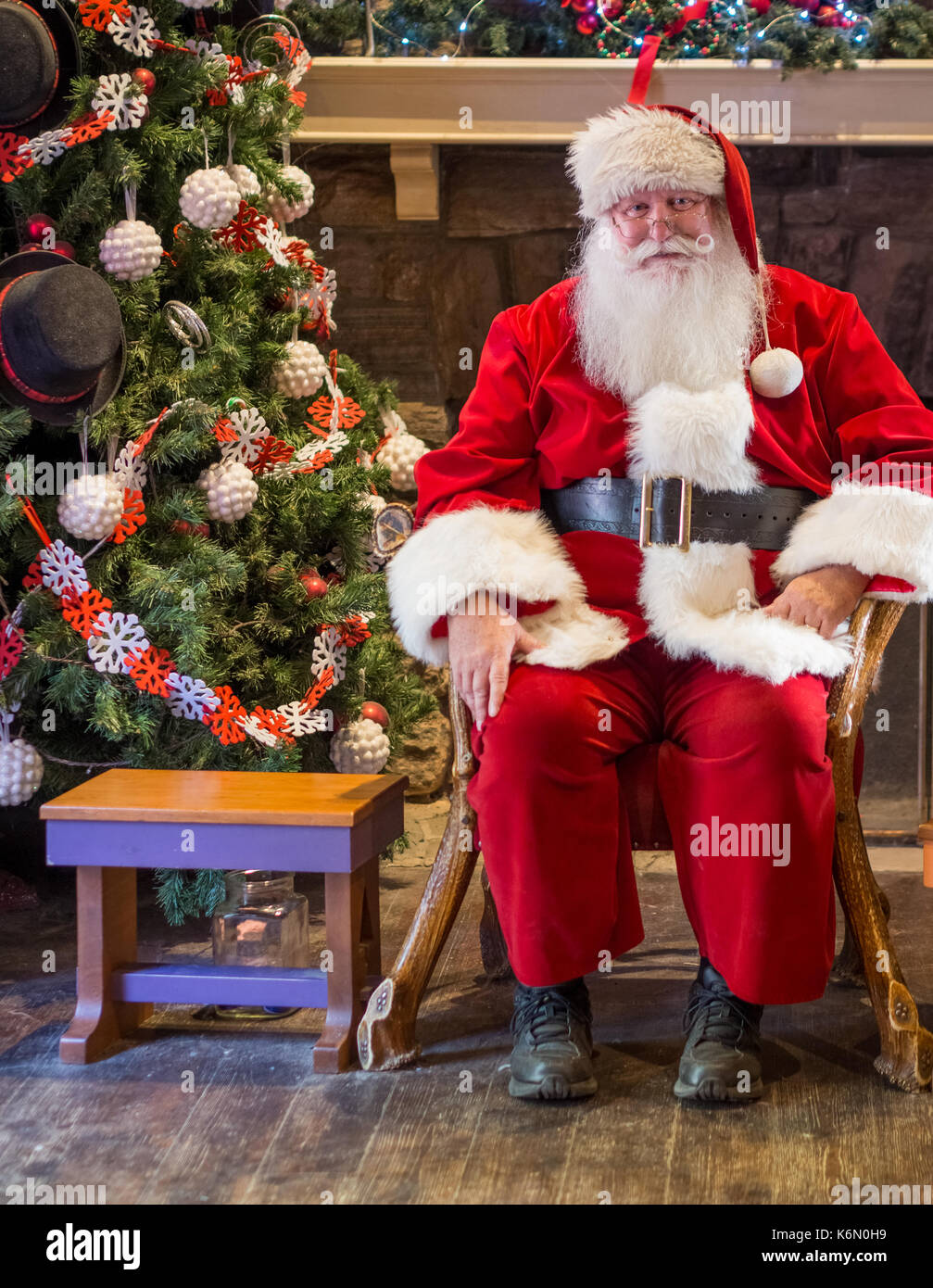 Sant warten auf Kinder zu erhalten, die ihren Urlaub in ein Hallenbad Einstellung geklickt haben. Der Hintergrund zeigt einen geschmückten Weihnachtsbaum mit Ornamenten. Stockfoto