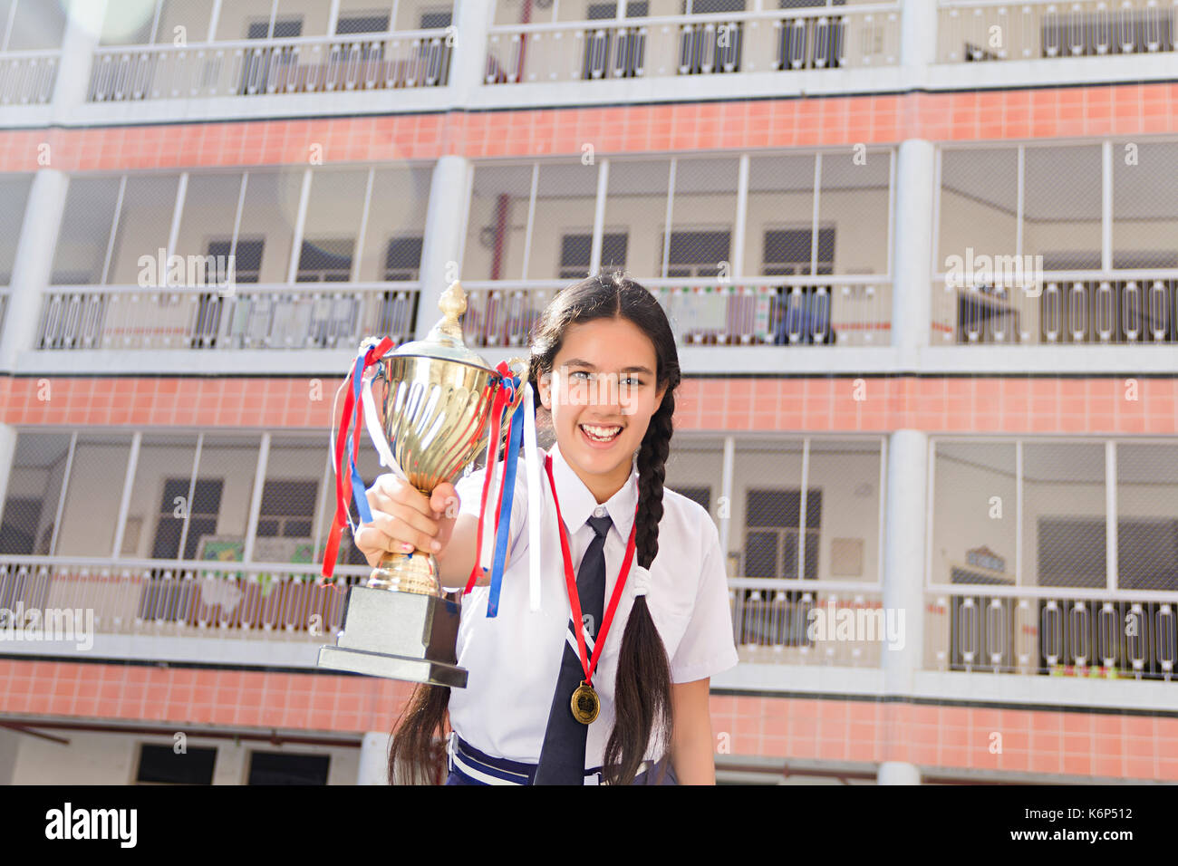 Happy 1 indischen Schule Teenager Girl Holding Trophy Gewinner erfolgreiche Ausbildung stehende Schule außerhalb Stockfoto