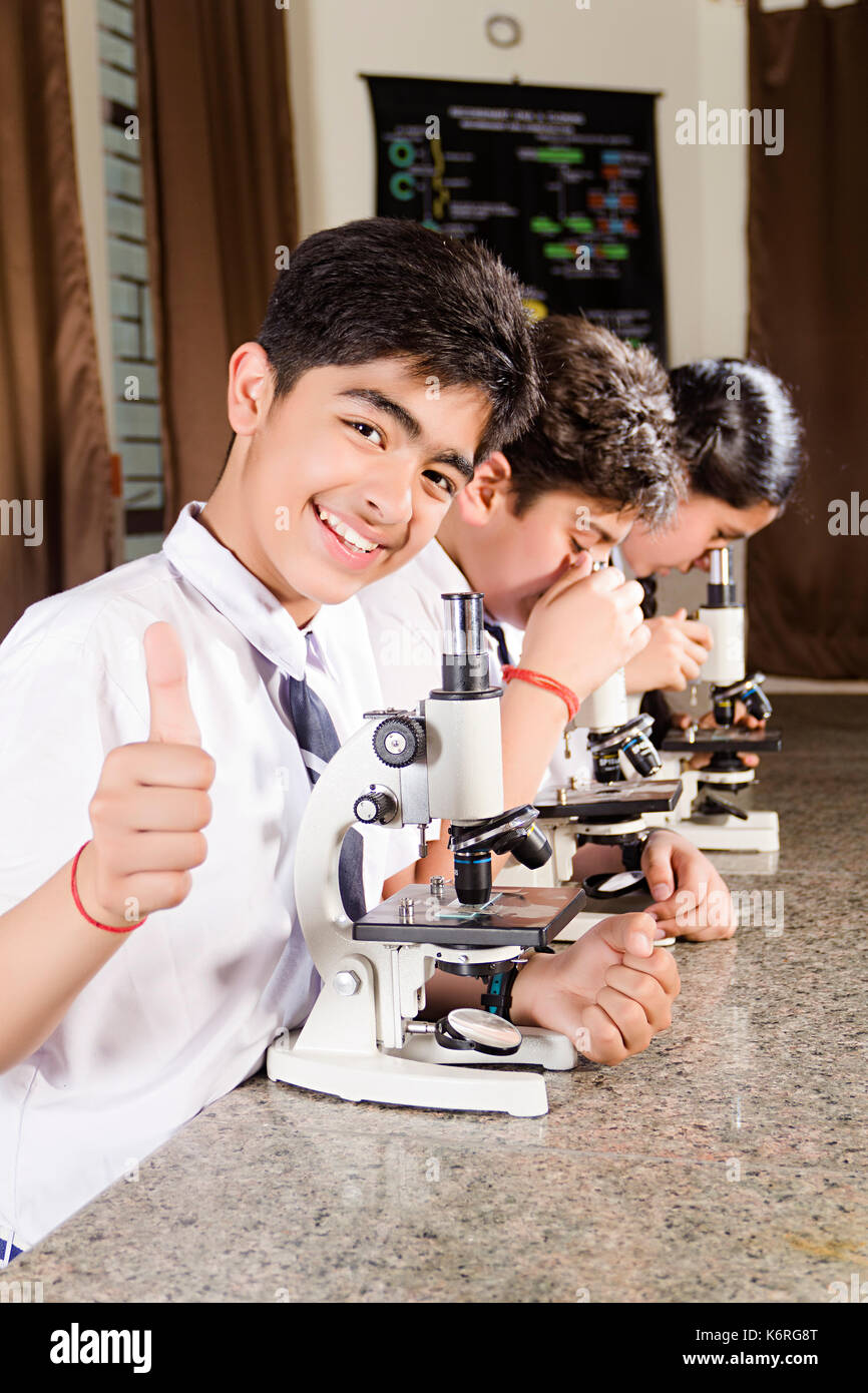 Indische Schule Schüler Mikroskop Science Lab Forschung und zeigen Daumen hoch Stockfoto