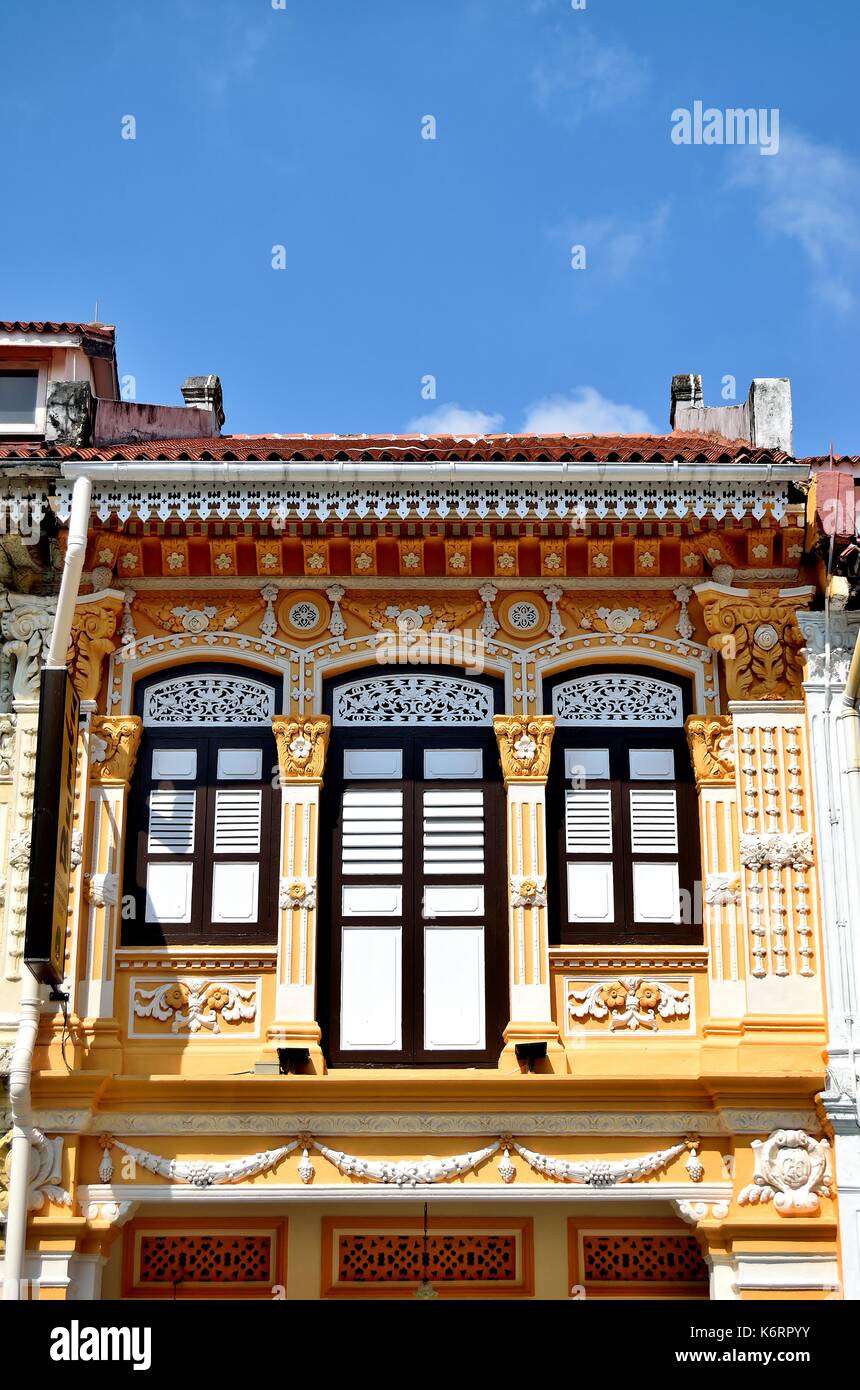 Traditionelle Singapur shop Haus mit orangefarbenen Fassade, weiße hölzerne Lamellenfensterläden und verzierten Säulen im historischen Kampong Glam Stockfoto