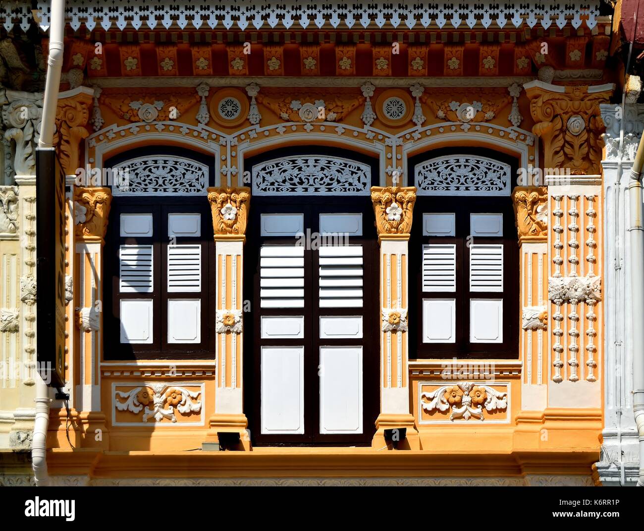 Traditionelle Singapur shop Haus mit orangefarbenen Fassade, weiße hölzerne Lamellenfensterläden und verzierten Säulen im historischen Kampong Glam Stockfoto