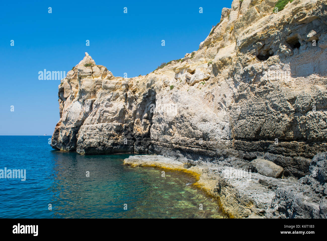 Eine Felswand entlang der maltesischen Küste, die Funktionen von Meer Erosion und Cliff Rezession. Wellenschnitt Plattform auf Meereshöhe und Risse und Felsbrocken. Stockfoto
