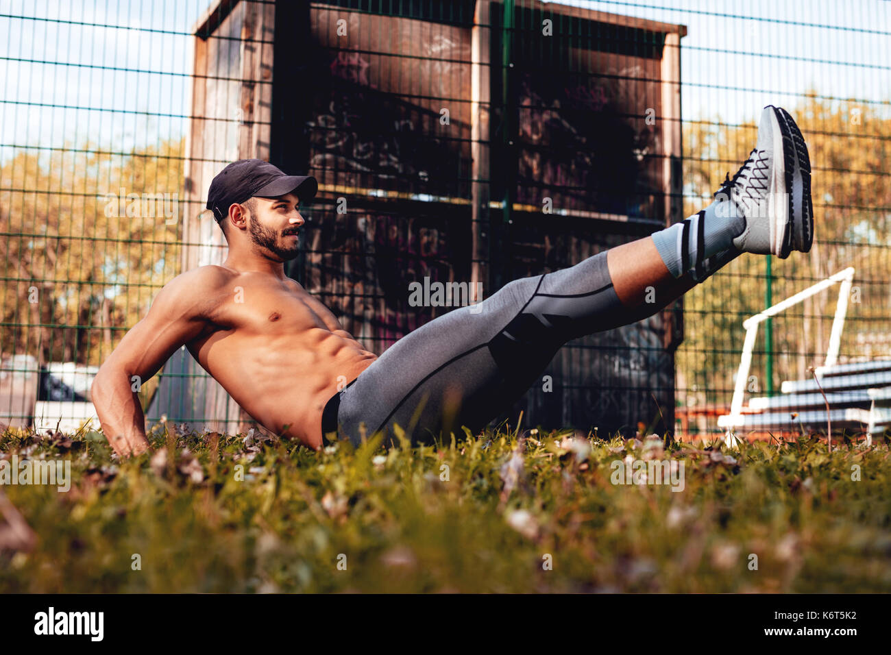 Junge, urbane, muskulöse Sportler tun, Sit-ups im Park. Stockfoto