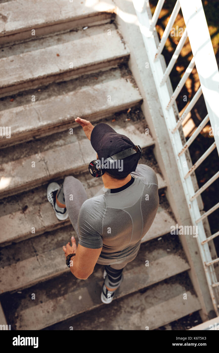 Junge muskulöse Sportler mit Kopfhörer zum Joggen, die Treppe an der Brücke. Stockfoto