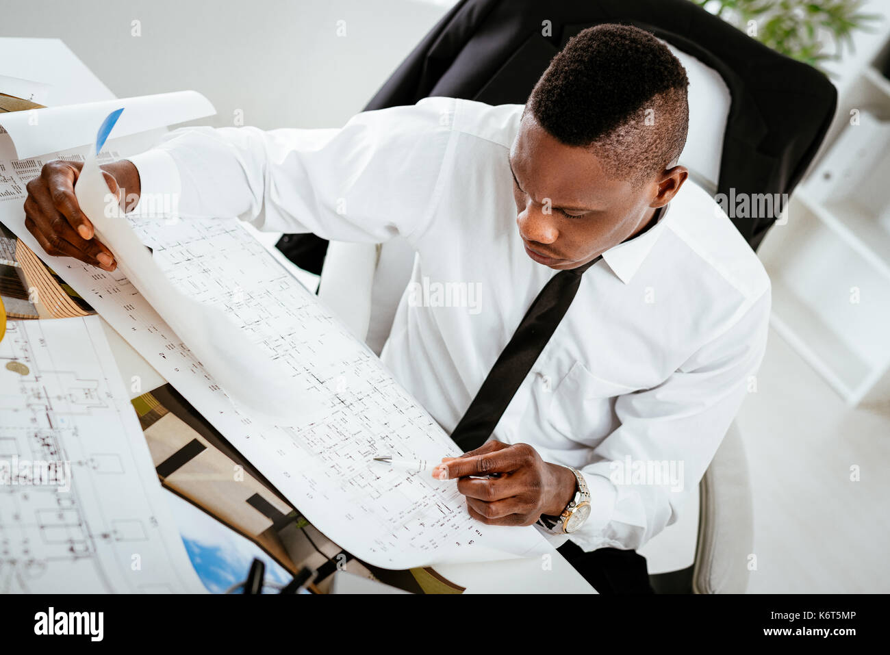 Nachdenklich afrikanischen Bauingenieur Analyse blueprint am Schreibtisch im Büro. Stockfoto