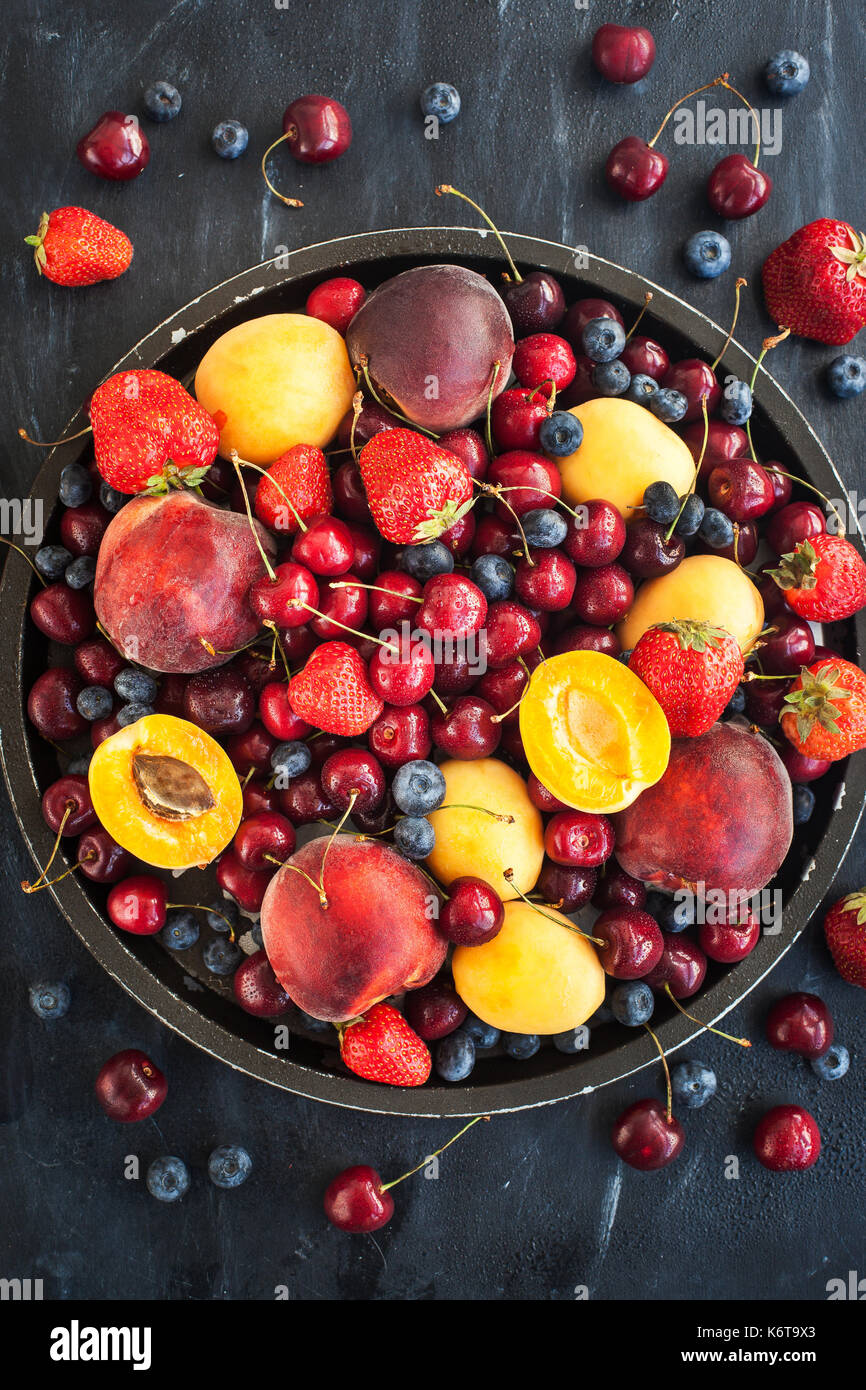 Frische reife Sommerbeeren und Früchte (Pfirsiche, Aprikosen, Kirschen und Erdbeeren) auf Tablett Stockfoto