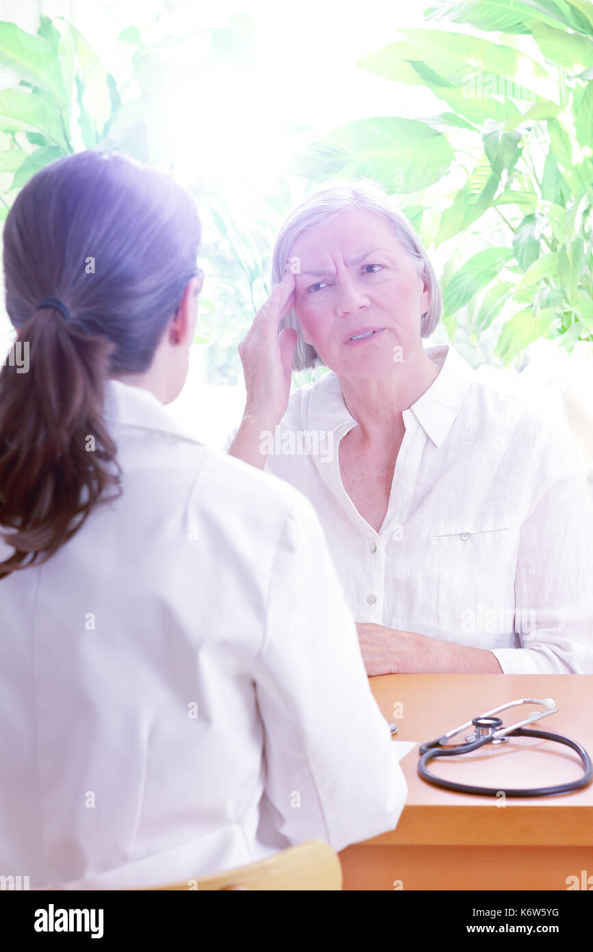 Frau Doktor mit Ihrer älteren Patienten mit Schlaf Probleme, Leid der Teilung Kopfschmerzen oder Migräne, Kopie Raum Stockfoto
