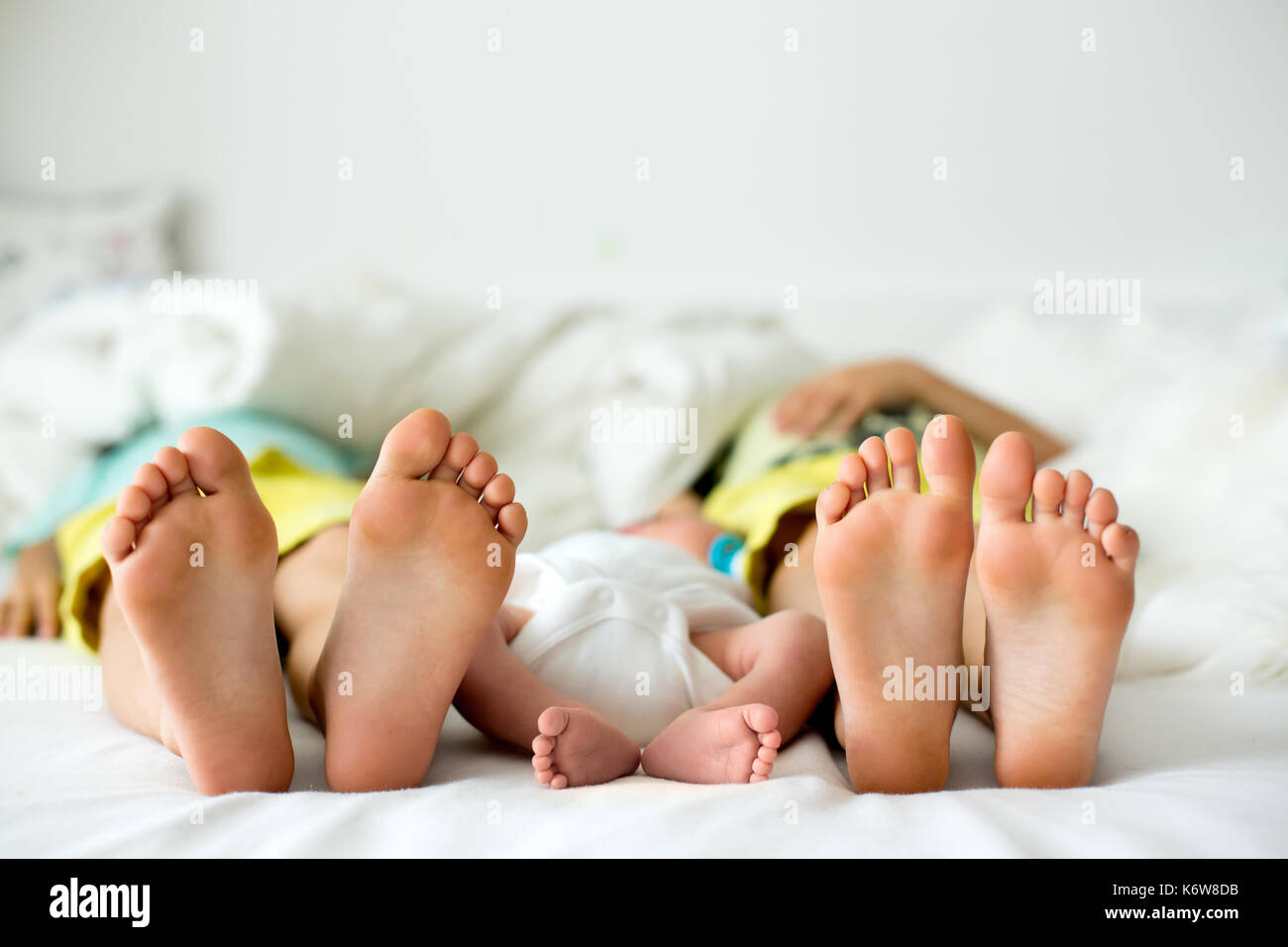 Drei Paar Füße, baby boy und seine beiden älteren Brüder liegen im Bett am Nachmittag, Tageslicht Stockfoto