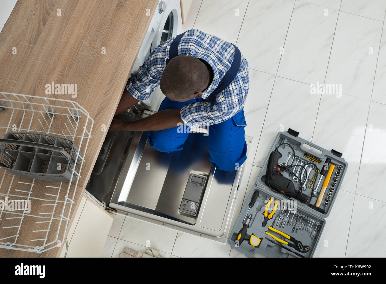 Junge afrikanische Techniker Reparatur Geschirrspüler in der Küche Stockfoto
