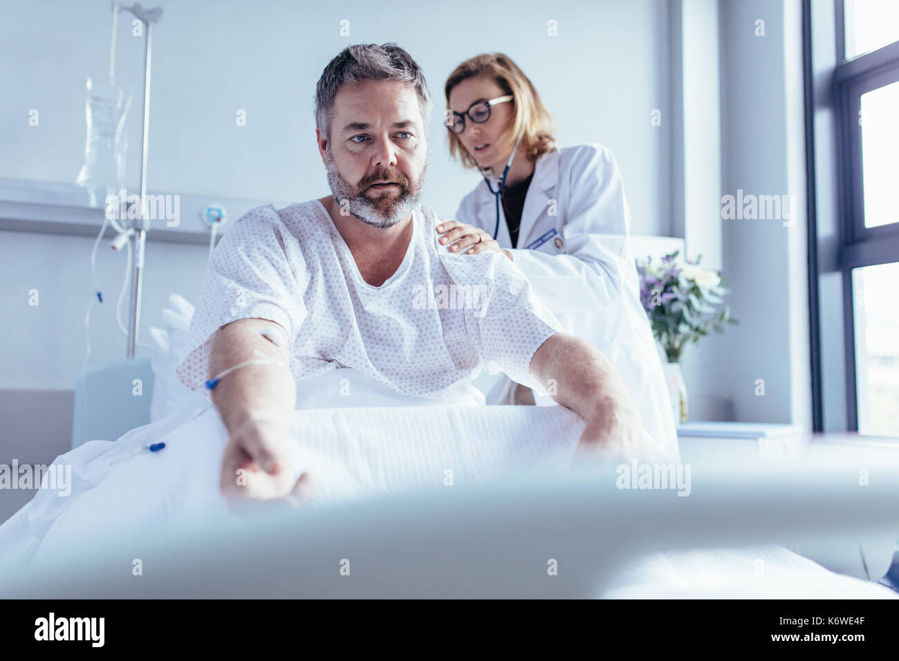Arzt Untersuchung reifer Mann im Krankenhaus. Patienten im Bett sitzen mit weiblichen Arzt seinem herzschläge. Stockfoto
