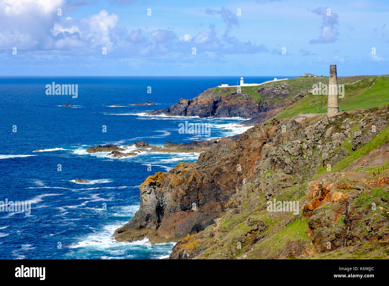 Felsige Küste mit alten Schornstein aus der Levante Mine und Pendeen Lighthouse, St Just in Penwith, Cornwall, England, Großbritannien Stockfoto