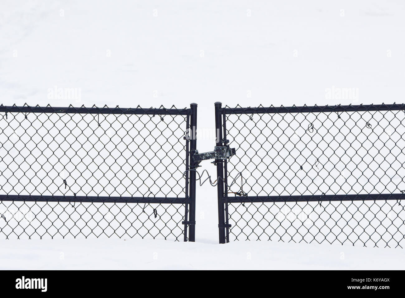 Geschlossen und verriegelt Maschendrahtzaun Tor auf einem schneebedeckten Auffahrt in Spekulant, New York NY USA Stockfoto
