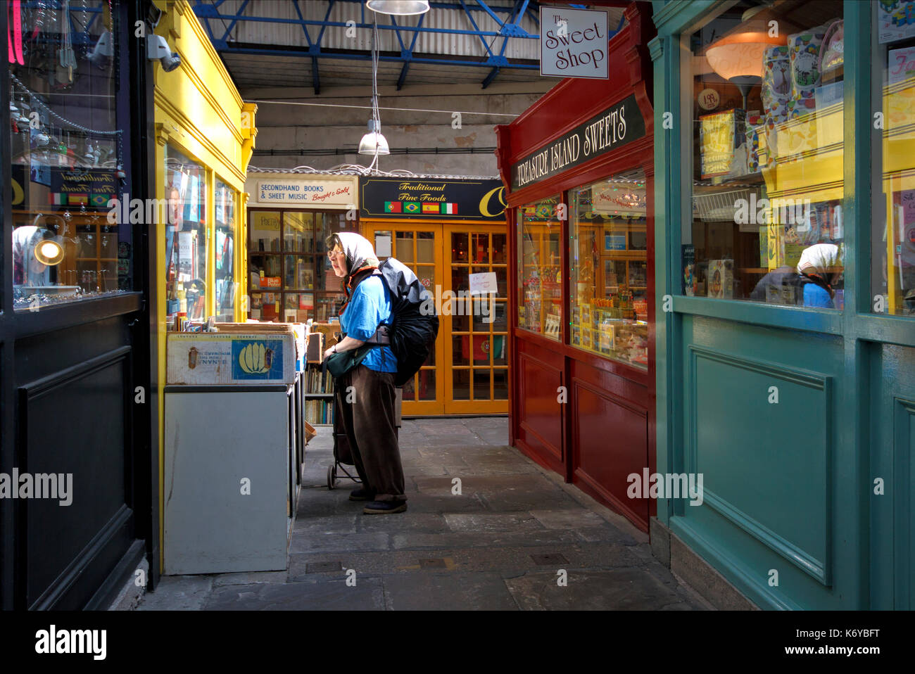 Eine ältere Frau durchsuchen Second Hand Bücher auf einem Tisch außerhalb eines second hand Book Shop. Es ist eine Markthalle, in Bristol, Großbritannien Stockfoto