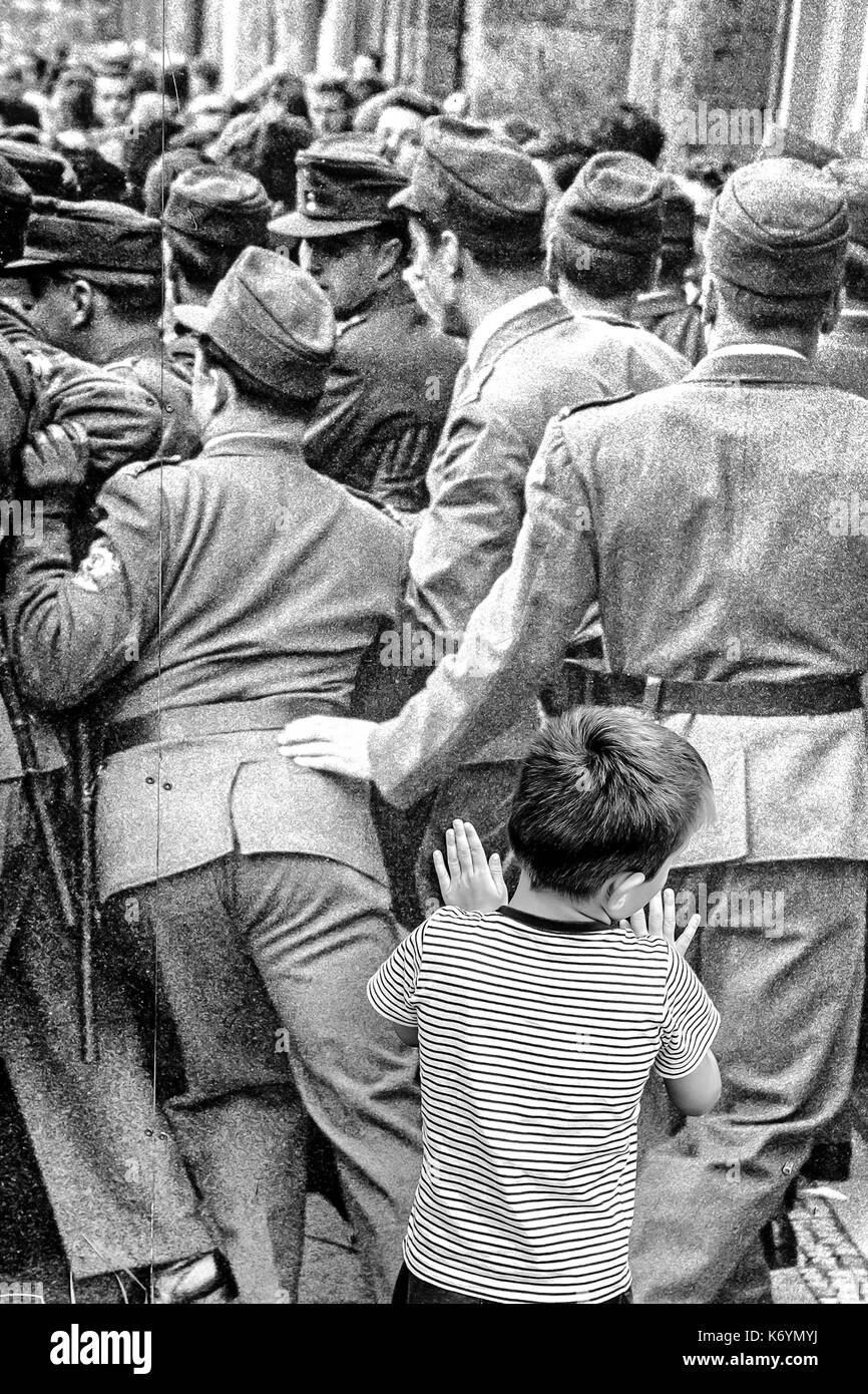 Deutschland ein Kind über ein Wandgemälde der Berliner Mauer lehnt, in der Nähe von Checkpoint Charlie, Berlin Stockfoto