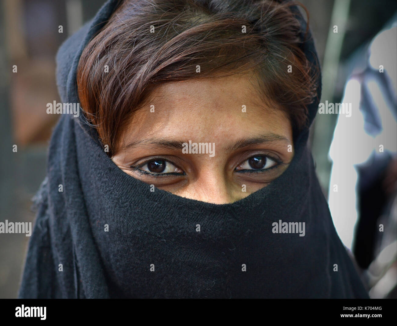 Der junge Inder Muslimah mit lächelnden Augen trägt einen legeren schwarzen Niqab und posiert für die Kamera. Stockfoto