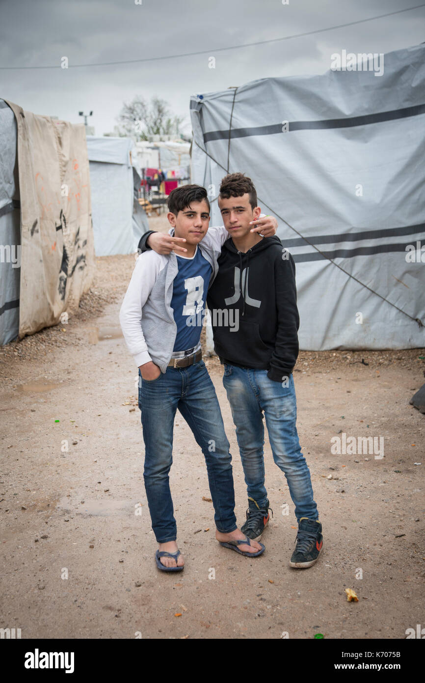 Zwei Jungen im Teenageralter, Resident in der Griechischen Ritsona Flüchtlingslager für die Syrer. Zwischen der Plane Eingang zu den Wohnungen, Sie schauen in die Kamera. Stockfoto
