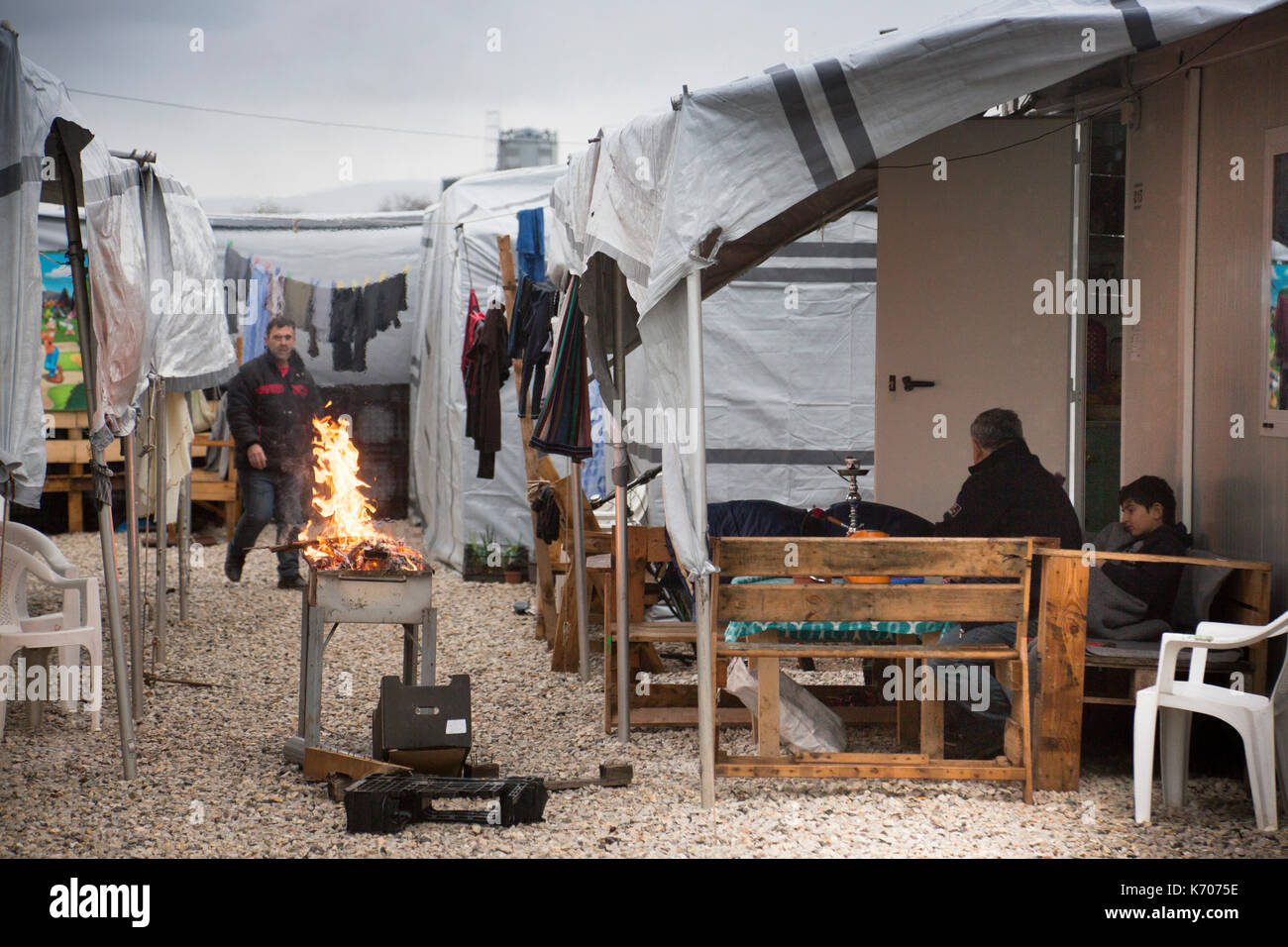 Ein Barbecue in der Vorbereitung zwischen den Zeilen von "Wohnungen Isobox" auf einem grauen Tag in Ritsona Flüchtlingslager in Griechenland. Stockfoto