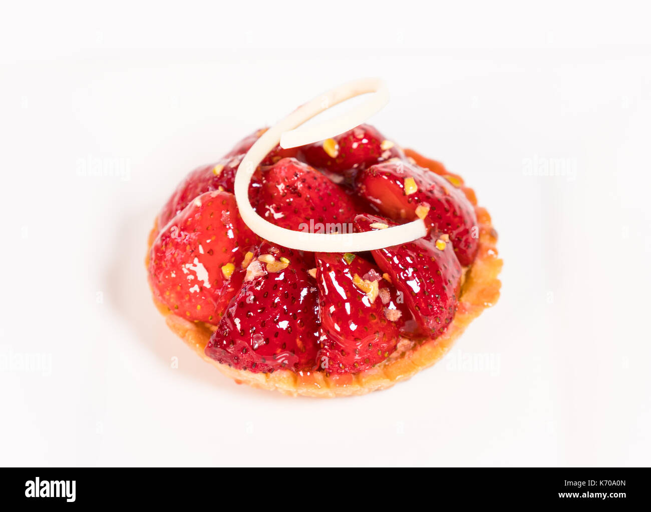 Ein Stück Erdbeere Törtchen mit gehackten Mandeln oben auf weißem Hintergrund Stockfoto