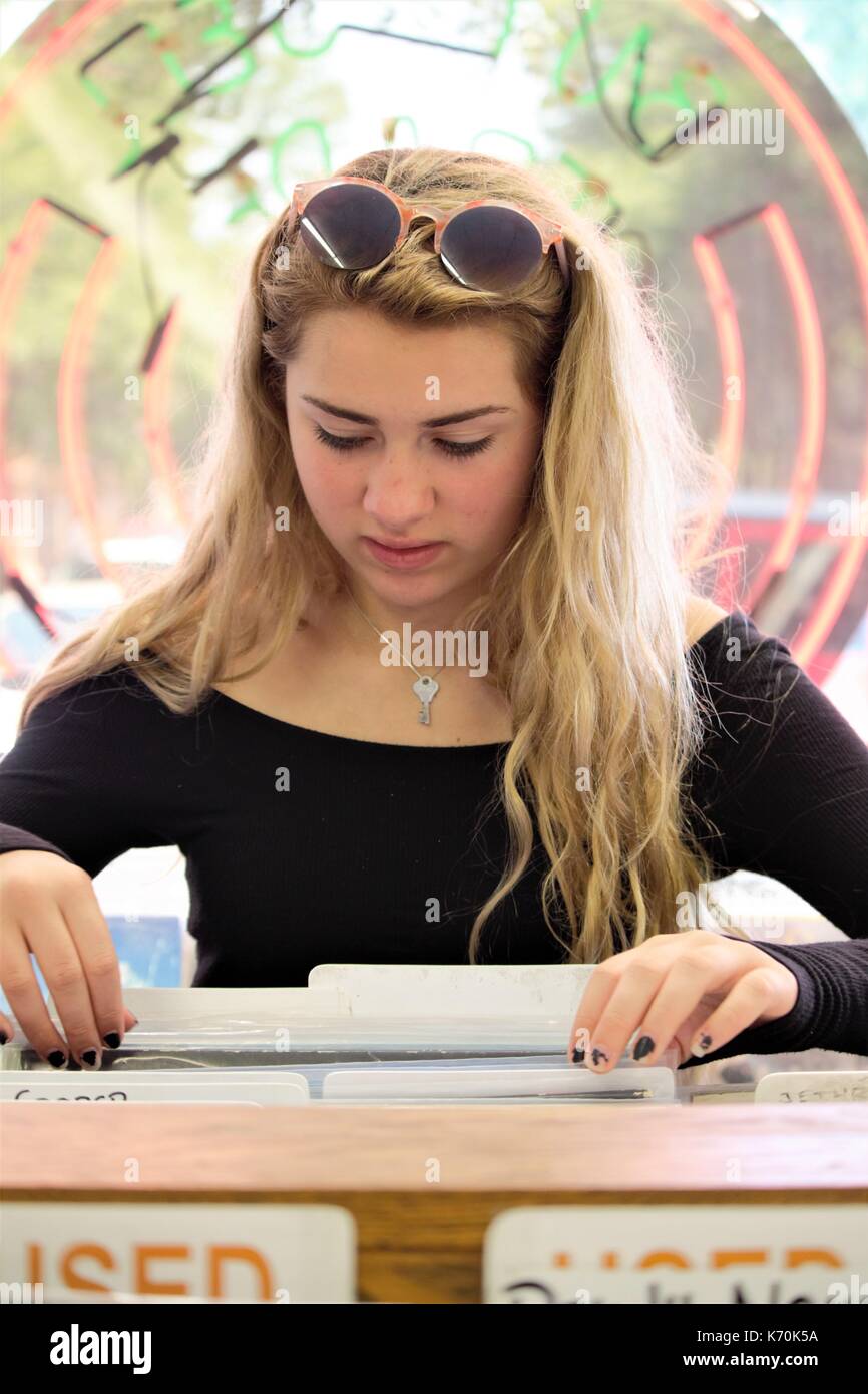 Blonde Teen Girl auf der Suche nach Alben in einem Datensatz zu speichern. Stockfoto