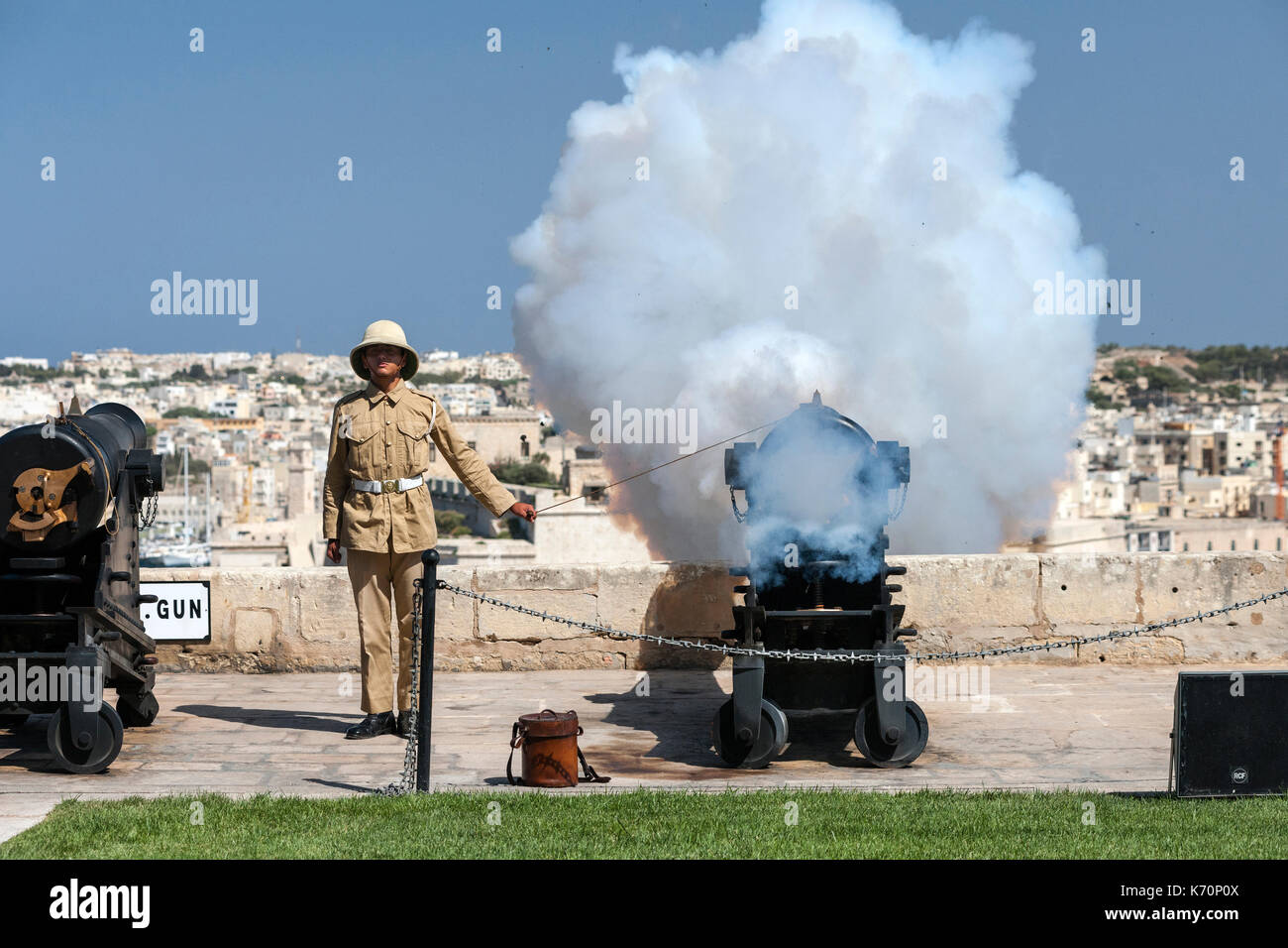 Eine junge gunner Brände Maltas 12.00 Uhr Kanone der Mittagshitze Stunde zu markieren. Die 12:00 Uhr gun Salute ist eine alte Tradition, dass der Marine wurde im Jahr 2004 gegründet und Oc Stockfoto