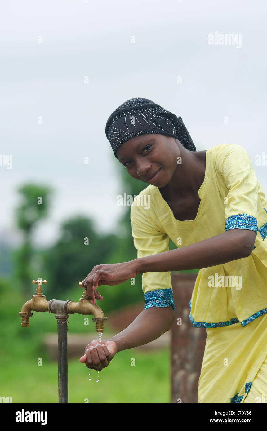 Junge schöne Afrikanische Mädchen im Freien halten sich an den Händen unter Wasser Leitungswasser Symbol für afrikanische Frauen Stockfoto