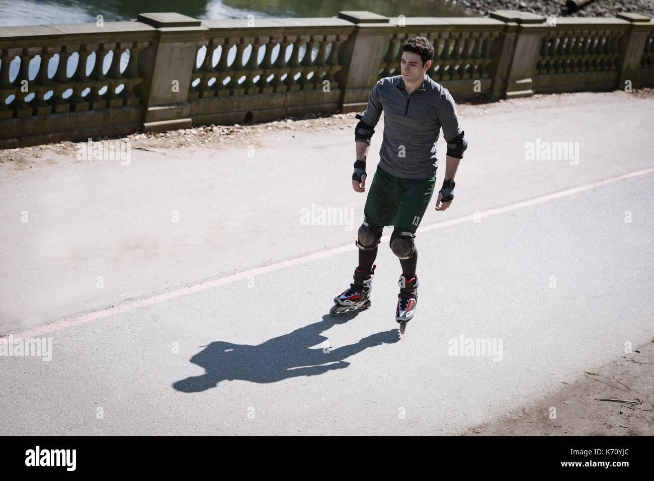 Volle Länge des jungen Mannes, Roller Skating auf Fußweg während der sonnigen Tag Stockfoto