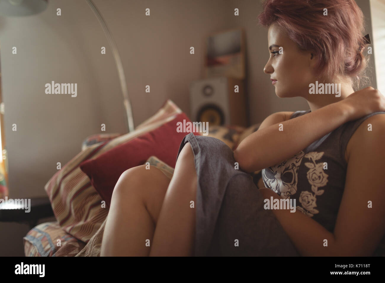 Nachdenkliche junge Frau auf dem Sofa zu Hause sitzen Stockfoto