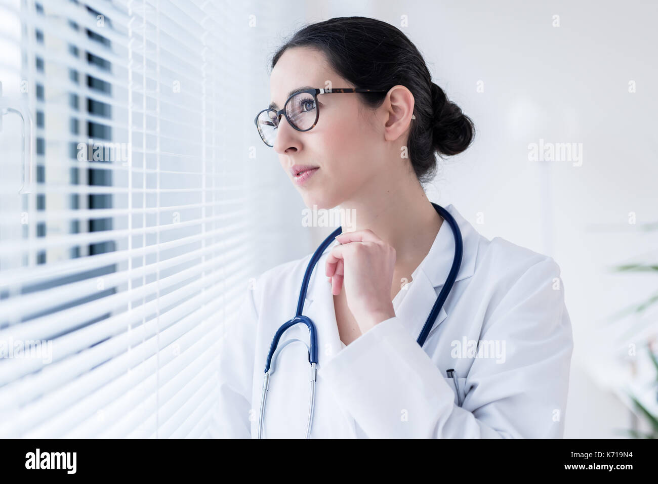 Junge Ärztin Tagträumen, während durch das Fenster suchen Stockfoto