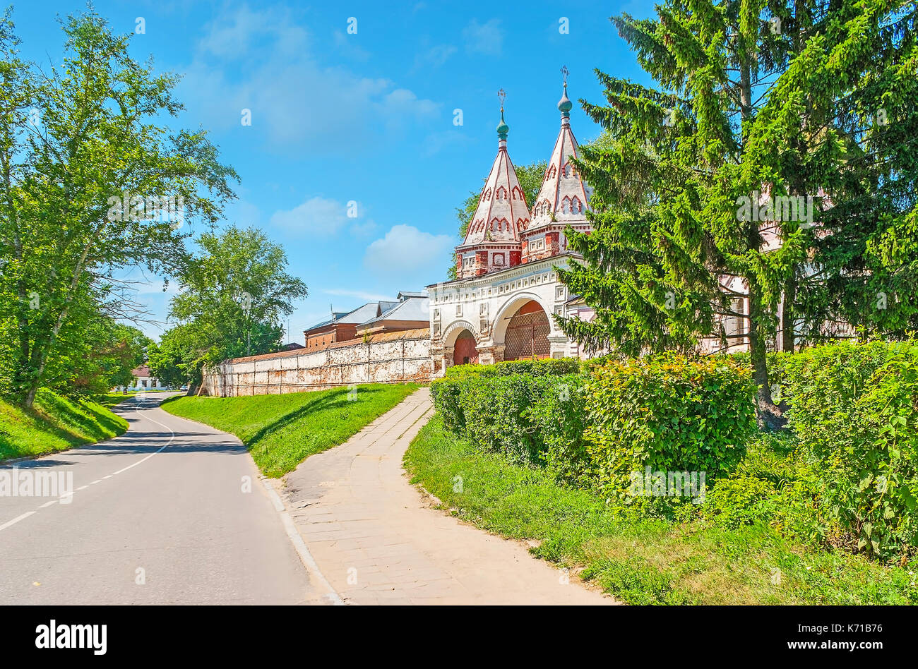 Der Blick durch die üppigen Tannen auf den Heiligen Pforten der Rizopolozhensky Kloster (Ablagerung von der Robe), dekoriert mit zwei Türmen und farbigen Patte Stockfoto