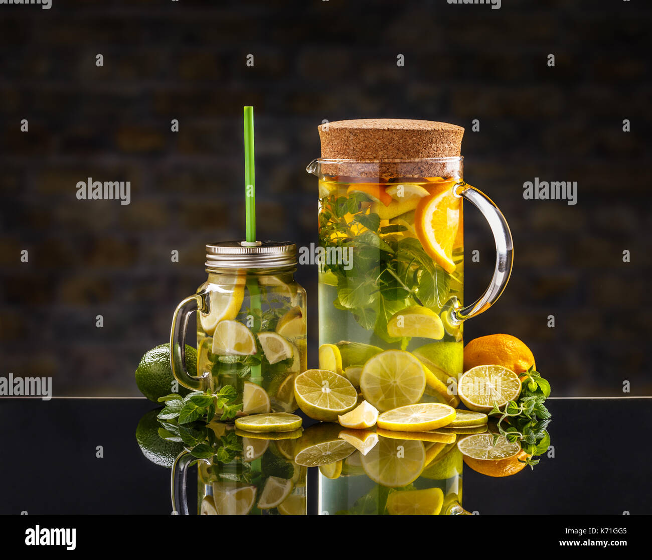 Kaltes Zitronenwasser mit frischen Früchten in einem Glas und in einem Krug Stockfoto