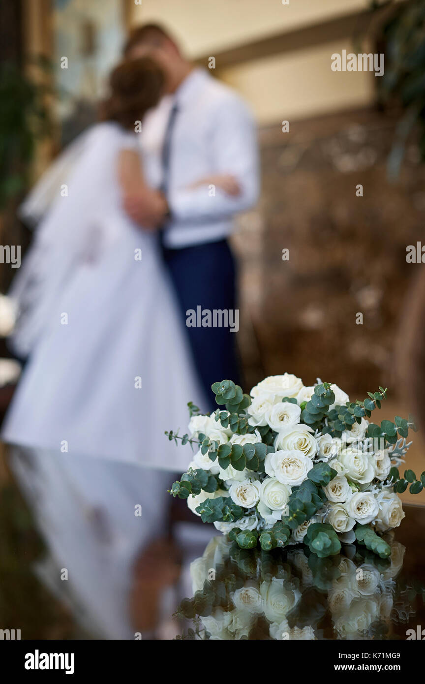 Schöne weisse Hochzeit Brautstrauß und auf dem Hintergrund Kuss der Braut und Bräutigam Stockfoto