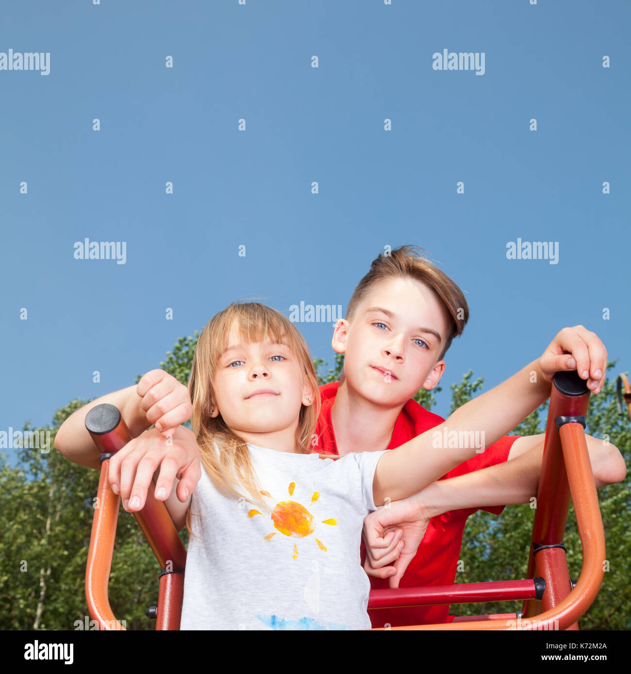 Low Angle View von Bruder und Schwester auf einem Klettergerüst im Sommer Spielplatz am Kamera Suche posing Stockfoto