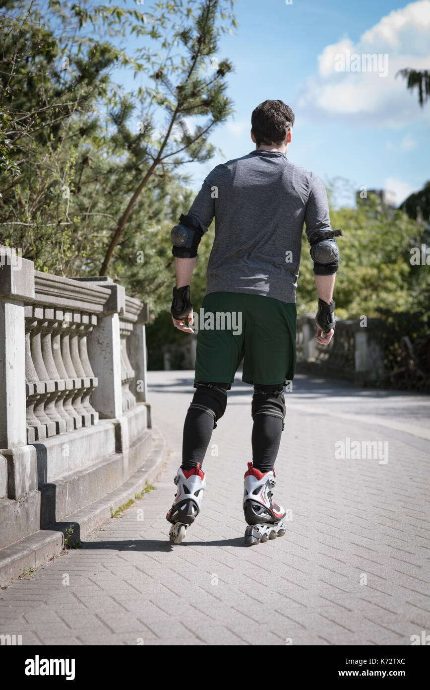 Ansicht der Rückseite des jungen Mann Skaten auf Fußweg während der sonnigen Tag Stockfoto